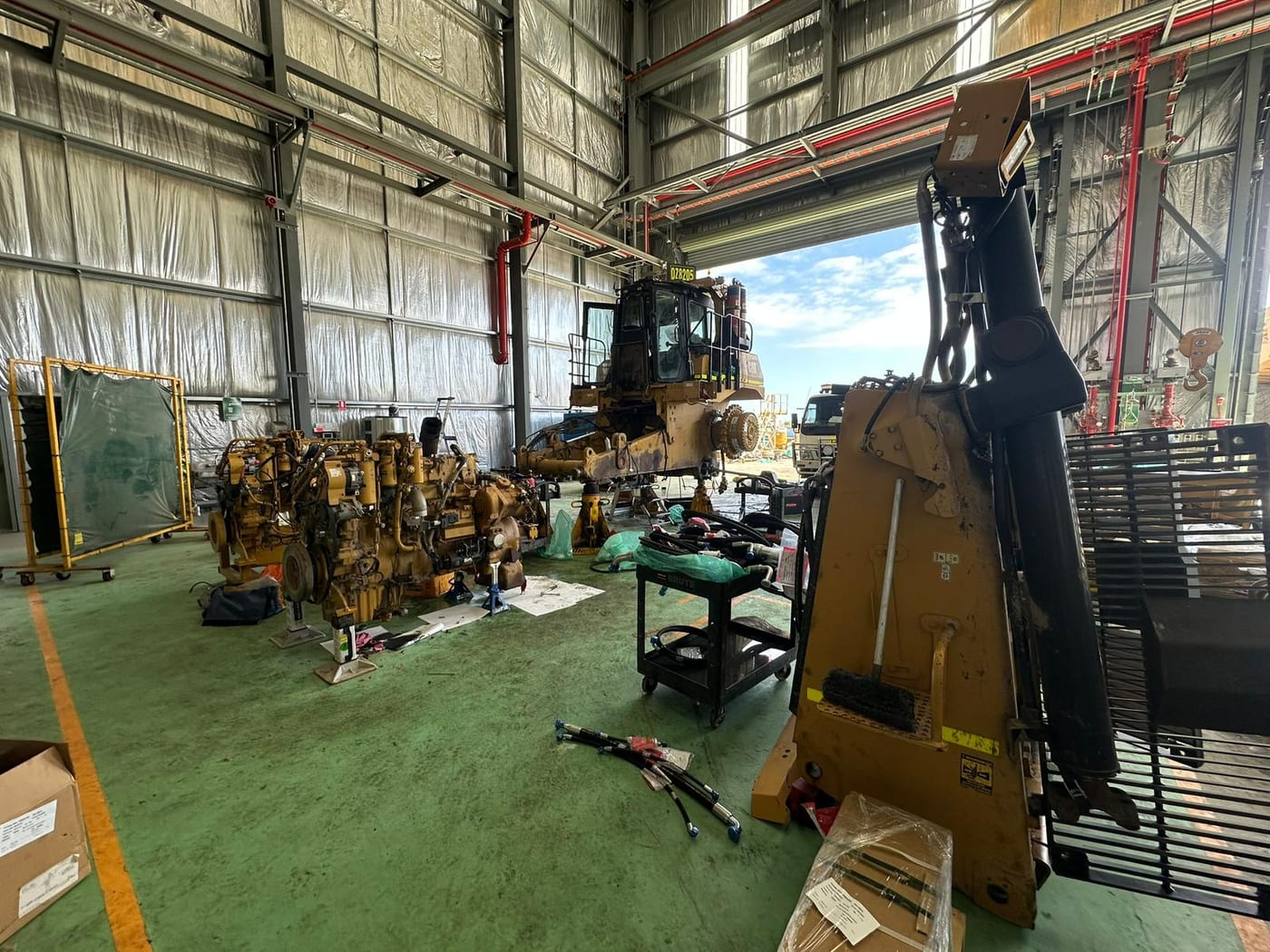 A grader being stripped down alongside engines on the workshop floor